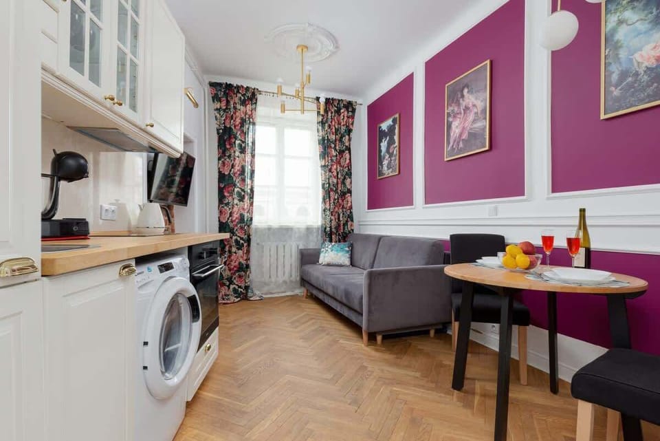 View of the harmonious combination of the living room with the kitchenette. The whole is elegant and stylish wall with elegant wainscoting and a pink wall gives the whole a unique character.