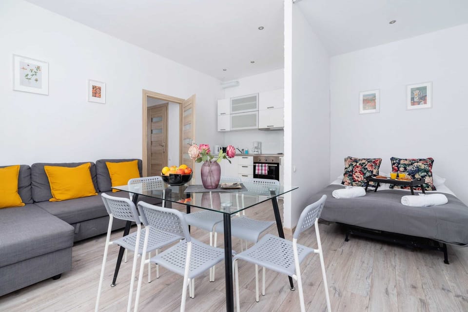 A modern living room featuring a gray sofa with yellow and colorful cushions, paired with a glass coffee table.