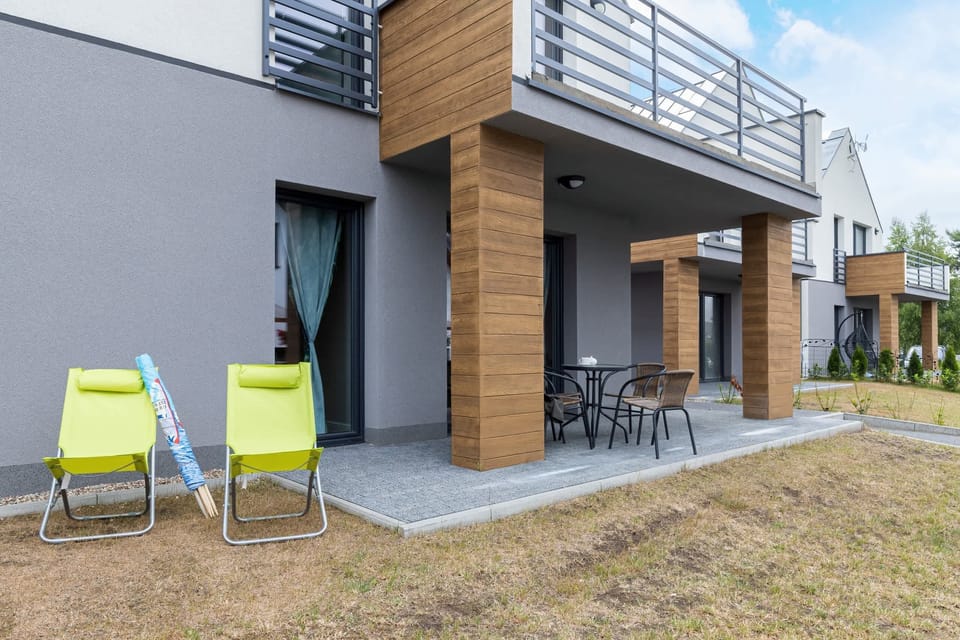A patio area with outdoor seating, part of a modern house with a wooden facade.