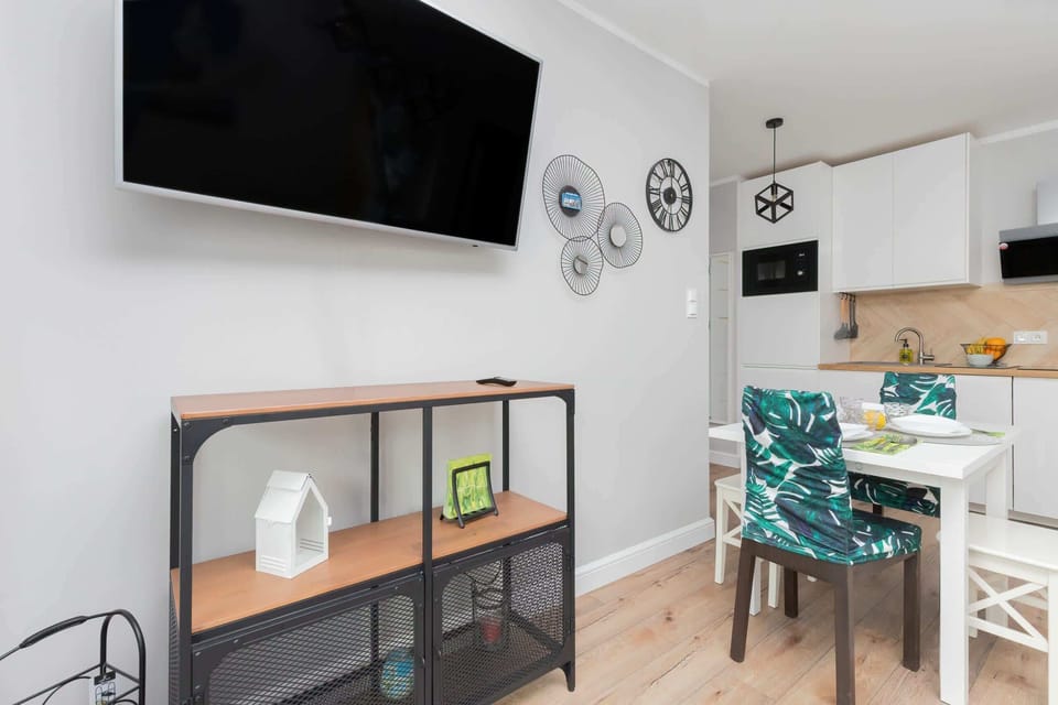 A corner of the living room with a mounted TV, a modern console table below it, and part of the dining space visible.