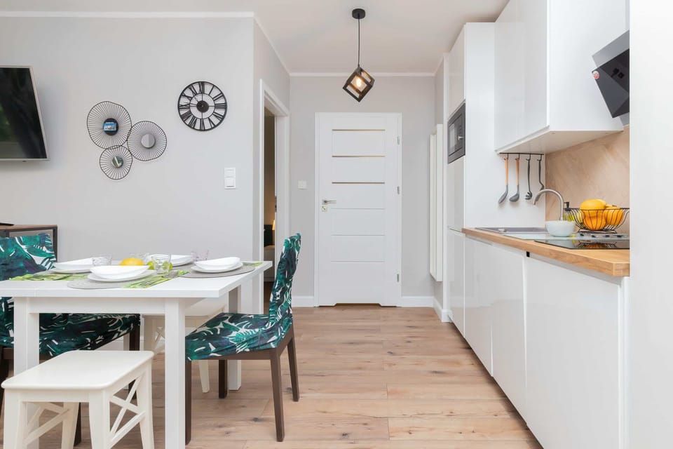 A combined dining and kitchen area, emphasizing the dining table and kitchen cabinets in white and wood tones.