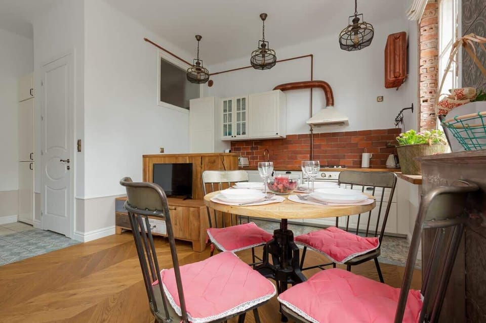 Close-up of the dining area with a round table and chairs. The photo shows a kitchenette and a cabinet with a flat-screen TV.