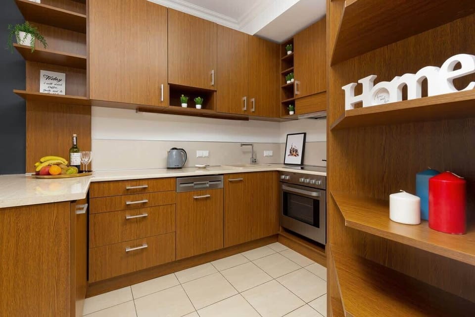 A kitchen with wooden cabinets, white tiles, and integrated appliances. The design is functional and compact.