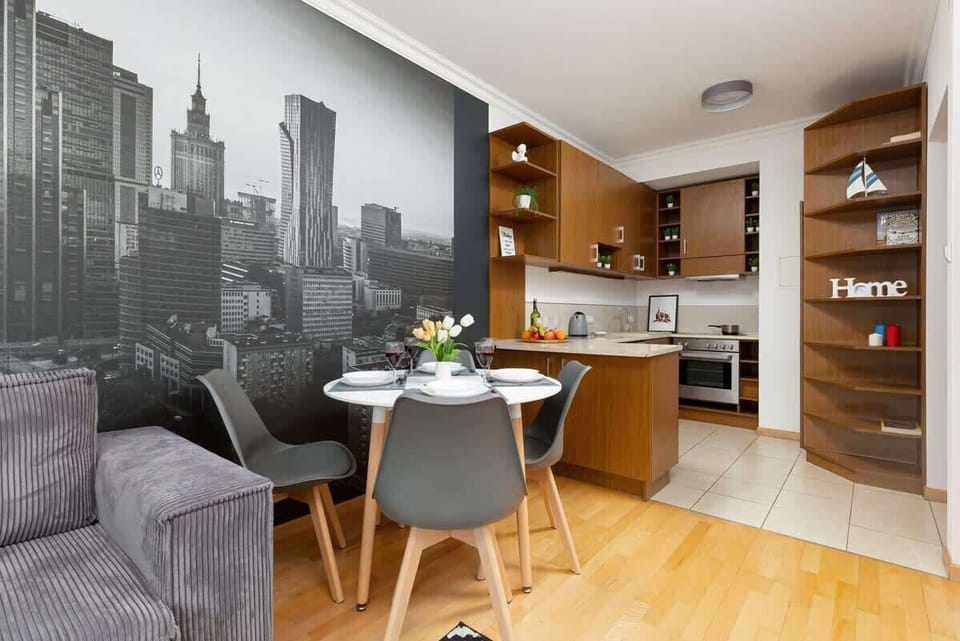 Another view of a living room with a light color scheme, cityscape mural, and a wooden dining table in the background.