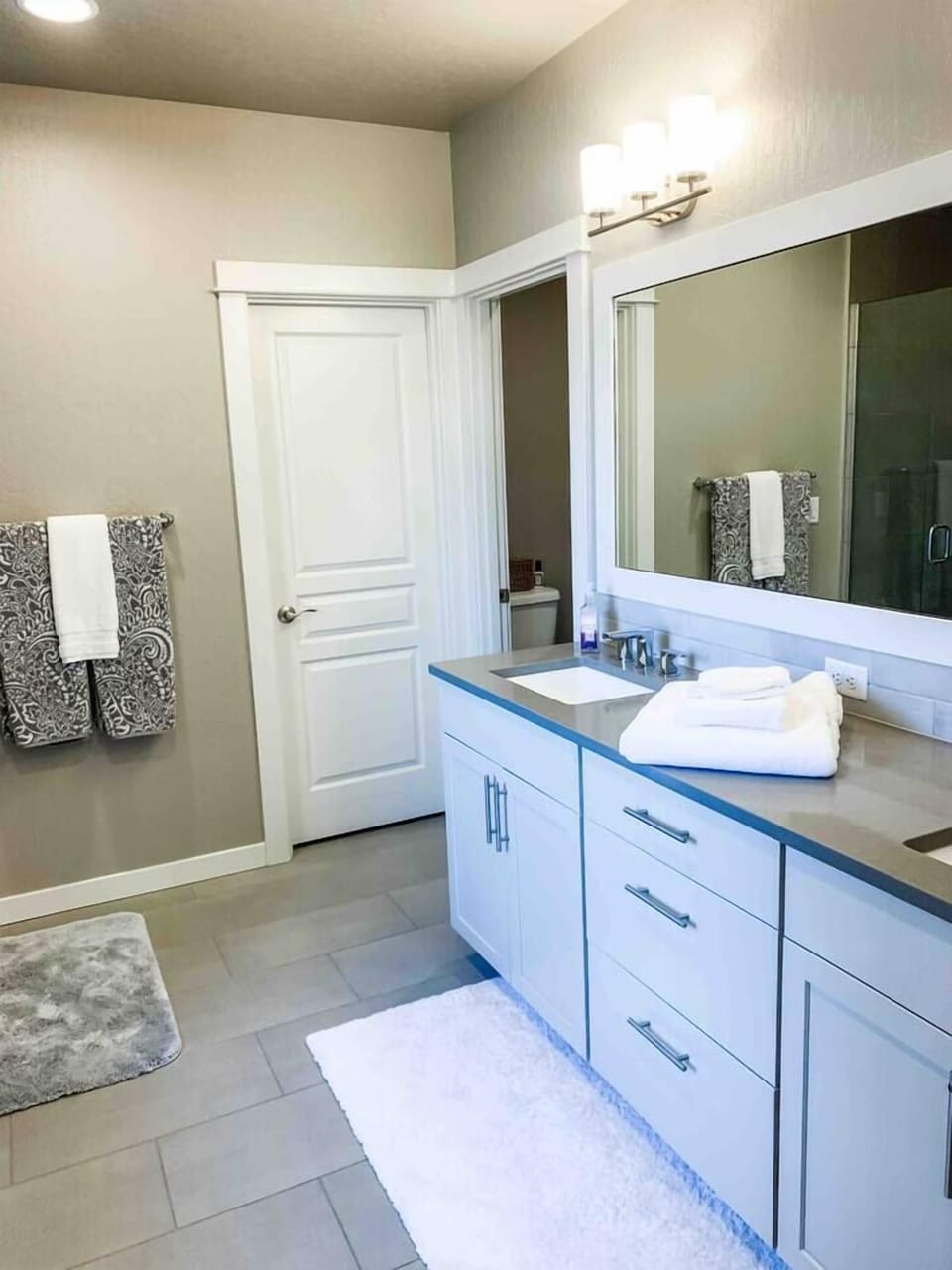 Main Level Master Bathroom features dual vanity, private toilet area, closet, large tiled shower, and huge bathtub (1)