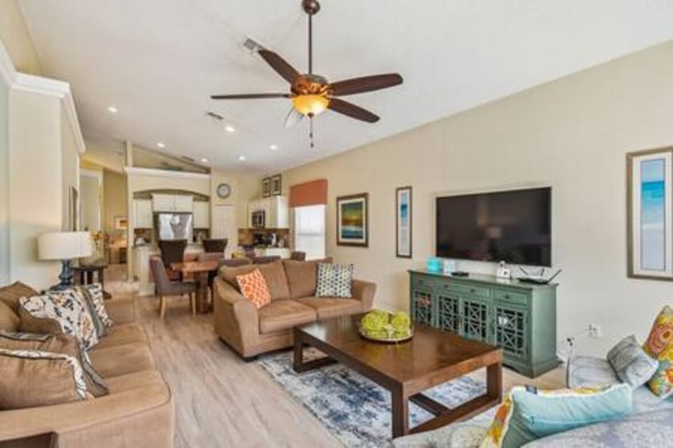 Welcome to a bright living area where natural light highlights light-colored walls and cozy sofas with colorful pillows. The stylish coffee table and decor create an inviting space, ideal for relaxing or socializing with friends.