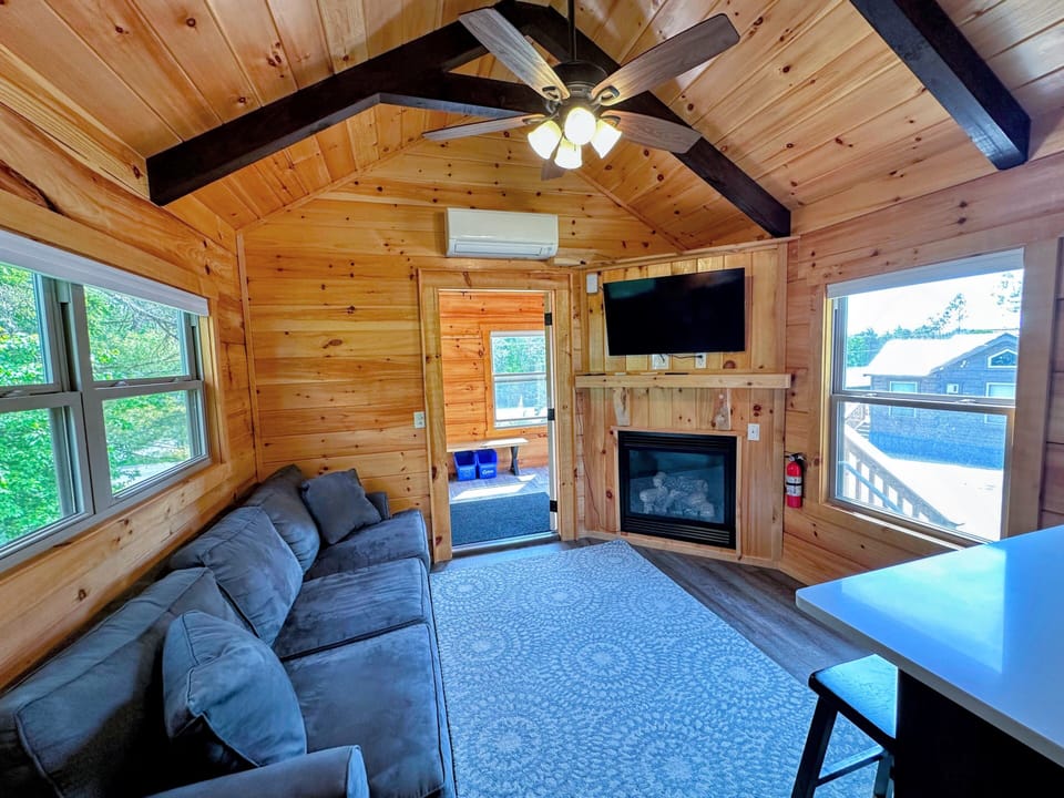 The main living space has a couch, TV, and gas fireplace with a table.