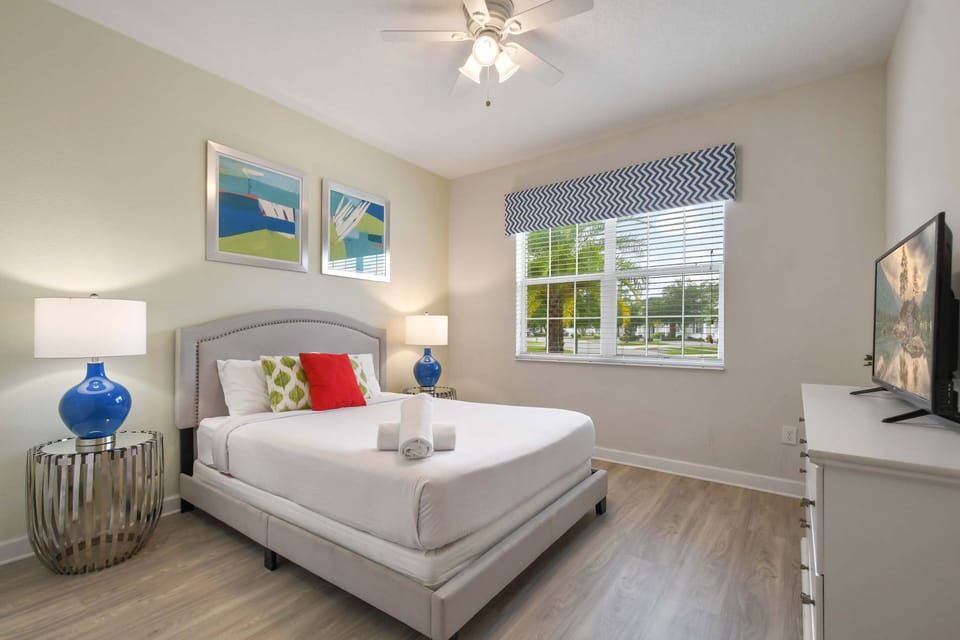 Vibrant bedroom with natural light, bold accents, and a smart TV for relaxing.
