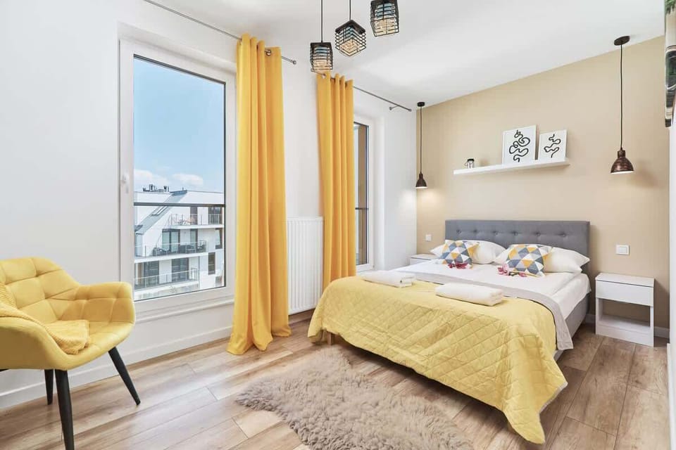 A bedroom with a large bed covered in yellow bedding, complemented by warm decor and natural light.
