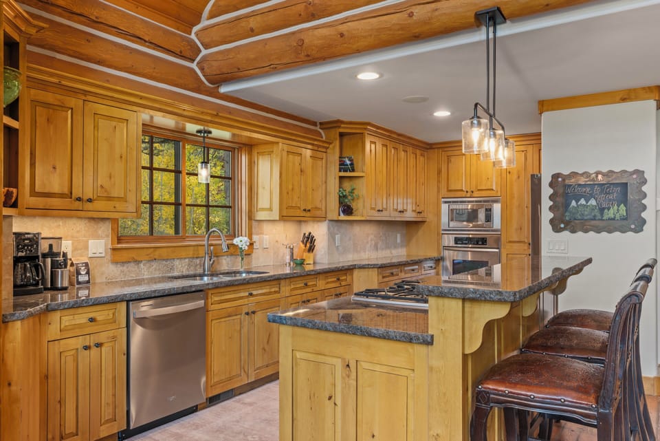 Step into your fully-equipped mountain kitchen where rustic charm meets modern convenience. Rich wood cabinets and granite counters create the perfect space for preparing hearty meals while you soak in forest views through the windows.