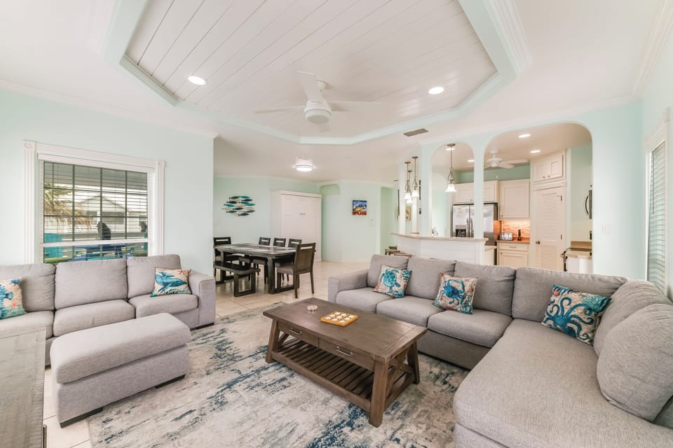 Sink into plush gray sectionals in this bright, open living space with coastal accents and soaring ceilings—your perfect gathering spot.