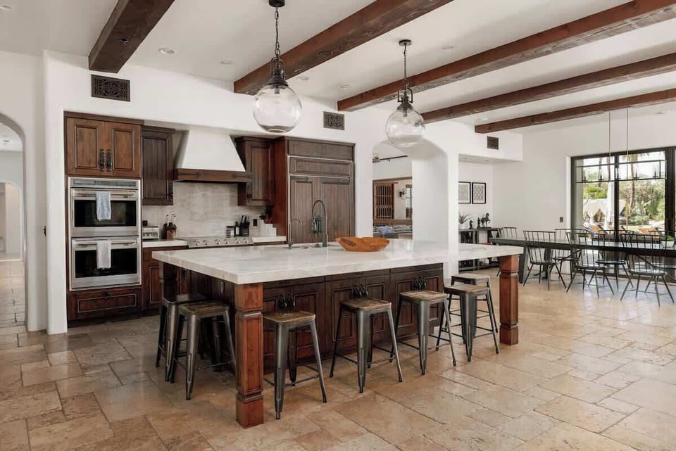 Your culinary haven awaits! Gather around the spacious island in this light-filled kitchen, where rich wood beams and elegant pendant lighting create a warm, inviting atmosphere for cooking and conversation.