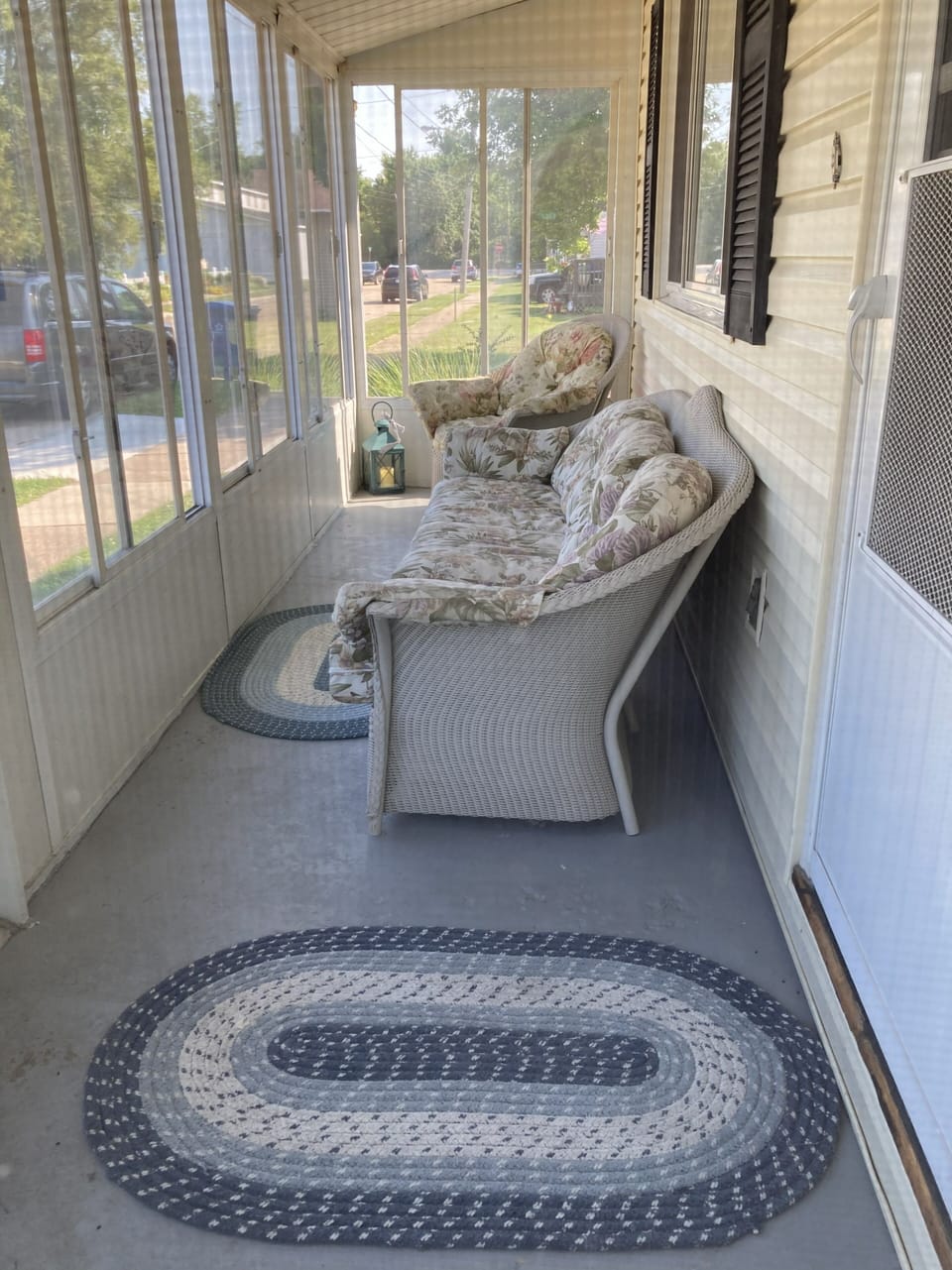 front door screened in porch with sliding glass/screen windows,  couches & rugs.