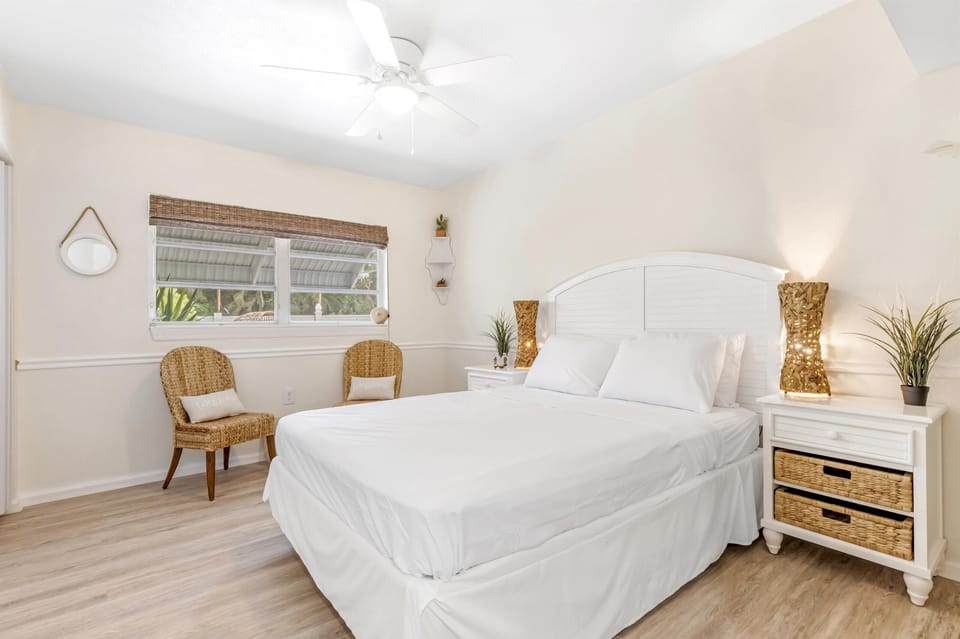 Bright bedroom with king bed, ceiling fan and reading chairs