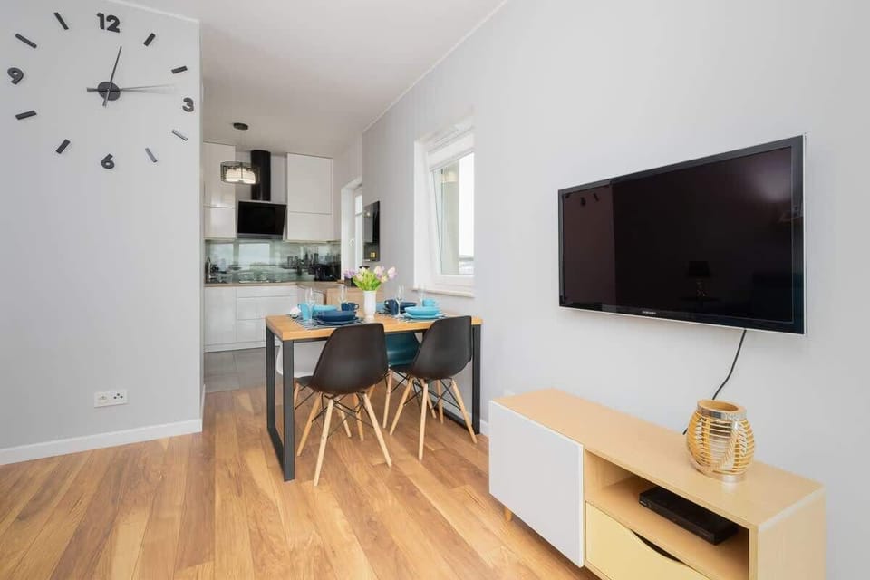 A modern living room showcasing a teal sofa, artistic wall decor, and small black tables for added functionality.
