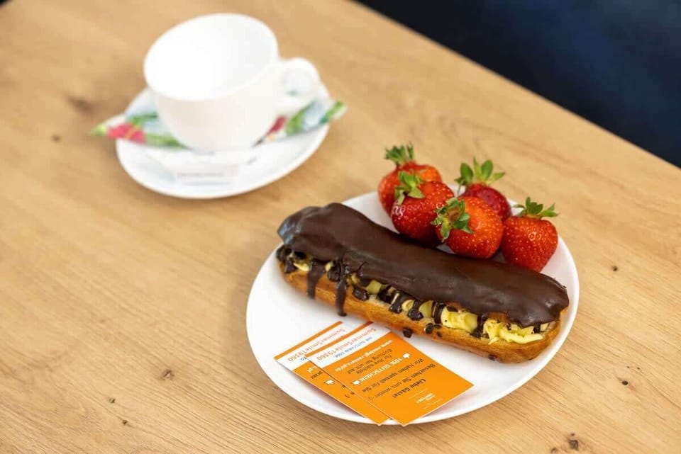 A close-up image of a breakfast spread on a wooden table, featuring a cup of coffee, strawberries, and a pastry, offering a cozy, homely feel to the apartment.