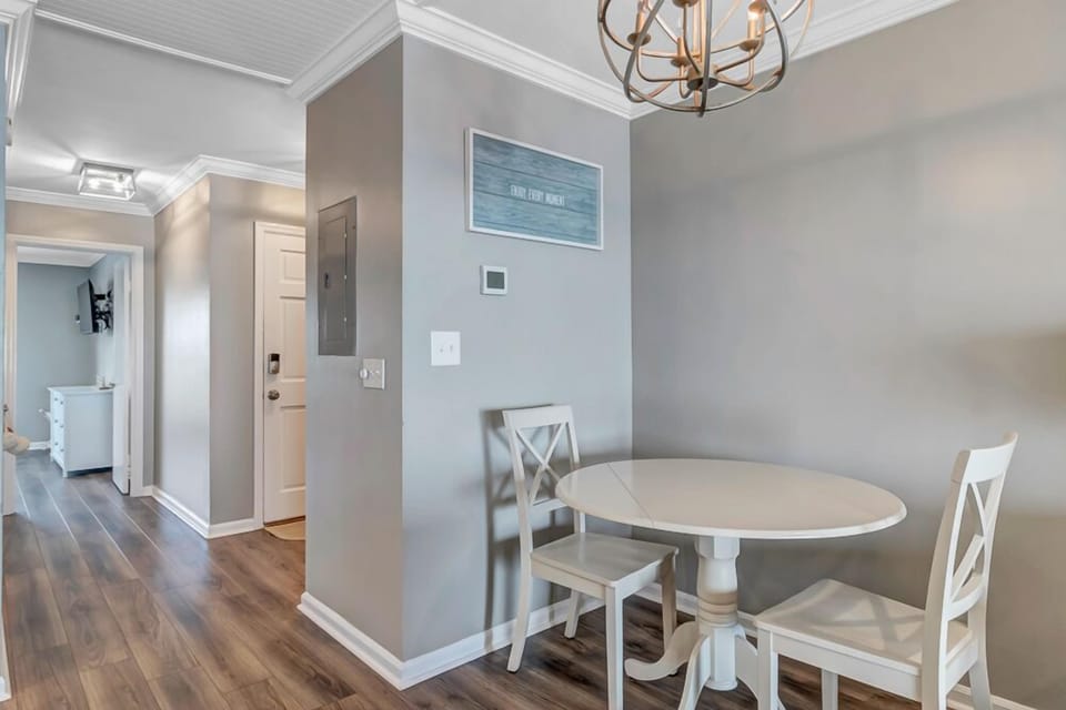 - Cozy dining nook for two with a white round table tucked under a chic chandelier
- Ideal spot for quiet breakfasts or evening card games in a relaxed atmosphere
- Soft gray walls and wood floors add warmth and modern simplicity