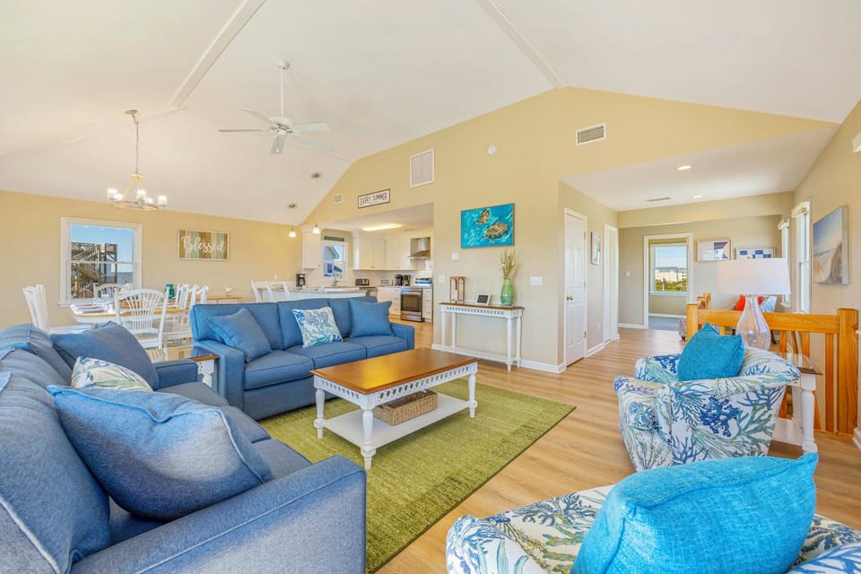 Sink into plush blue sofas in this bright, open-concept living space where coastal charm meets comfort for your perfect getaway.