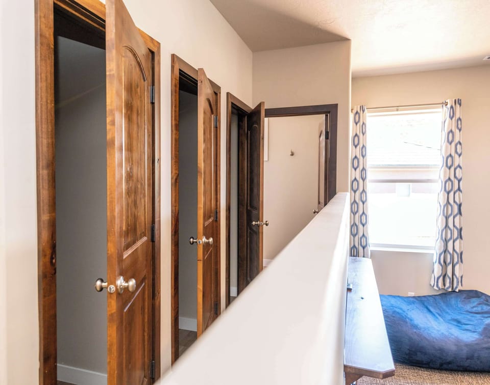 Cozy upstairs loft with built-in closets and geometric curtains — extra sleeping space at The Gathering Place, Kanab.