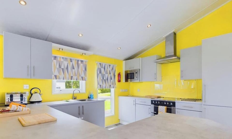 Fully equipped kitchen featuring a central island with bar stools, integrated dishwasher, and gas hob.