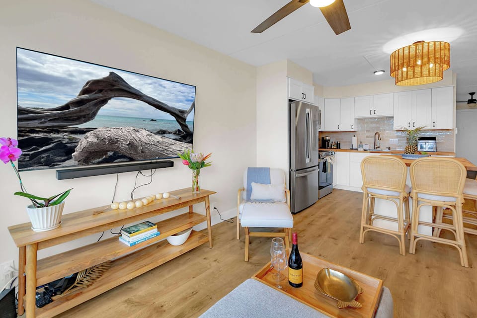 Puako Beach Condo #102 - Living Room and Kitchen with stainless steel appliances and island.