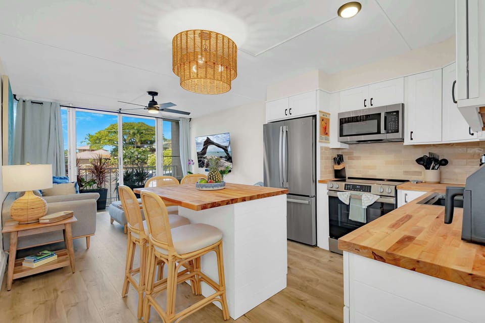 Puako Beach Condo #102 - Living Room and Kitchen with stainless steel appliances and island.