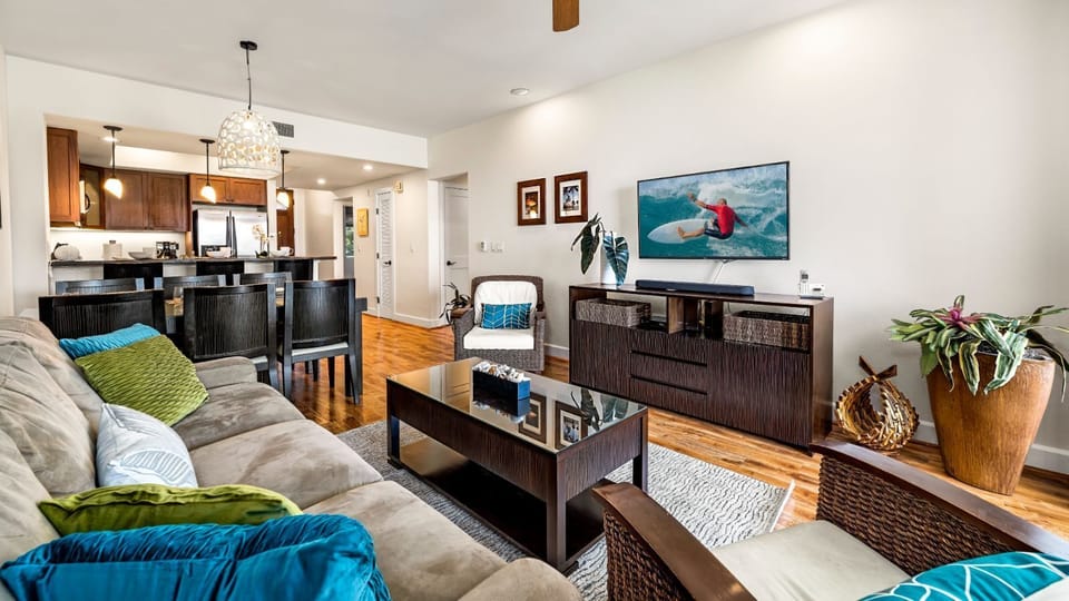 The living area includes a sofa sleeper, wall-mounted TV, and coffee table.