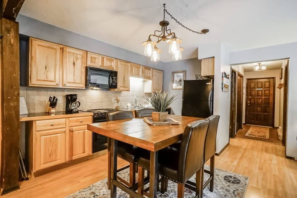 View of the dining area, fully-equipped kitchen, and front door