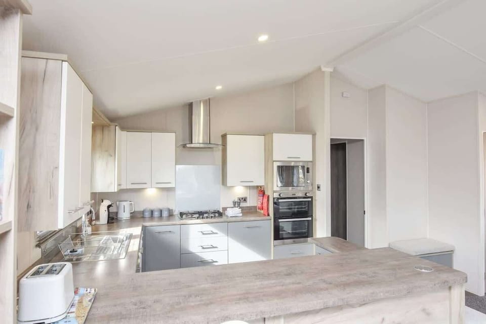 Bright kitchen and dining area at Rowan with modern appliances, breakfast bar and table seating.
