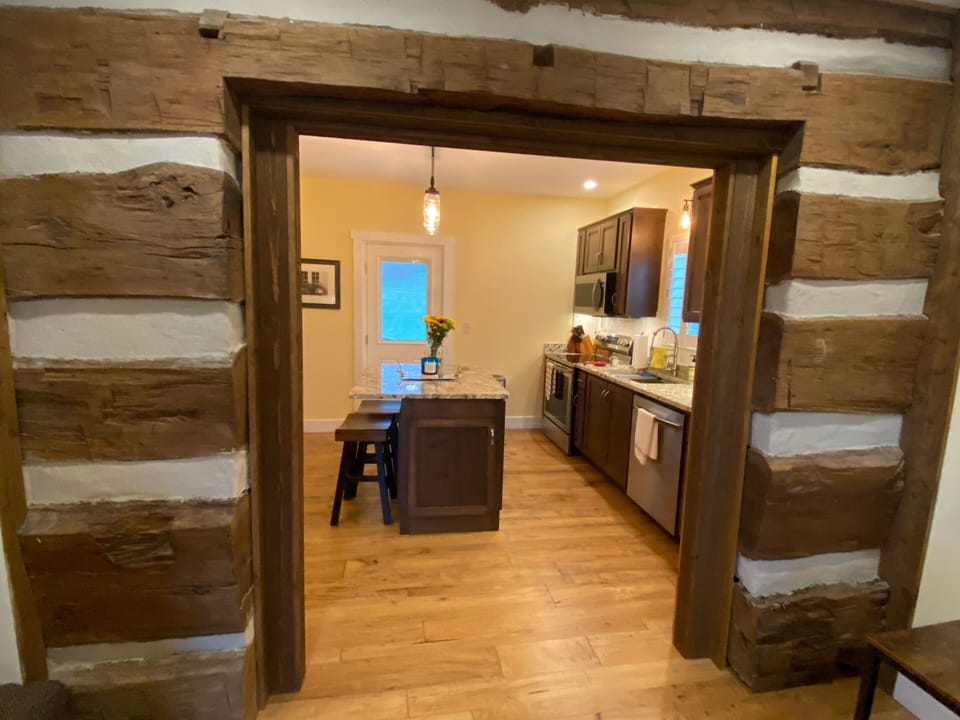 Living room original log wall enter into kitchen.