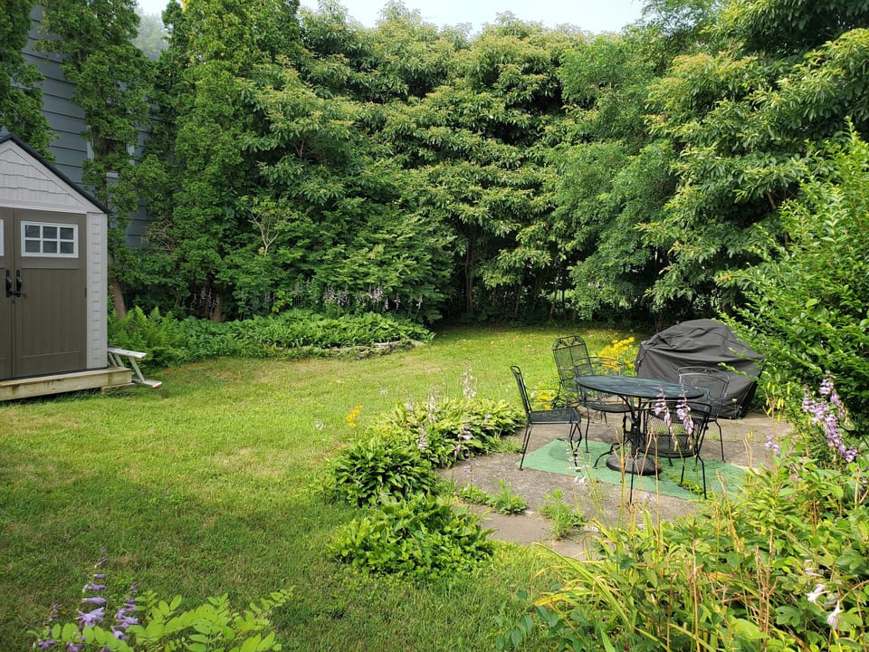 Large private back yard includes patio seating and grill