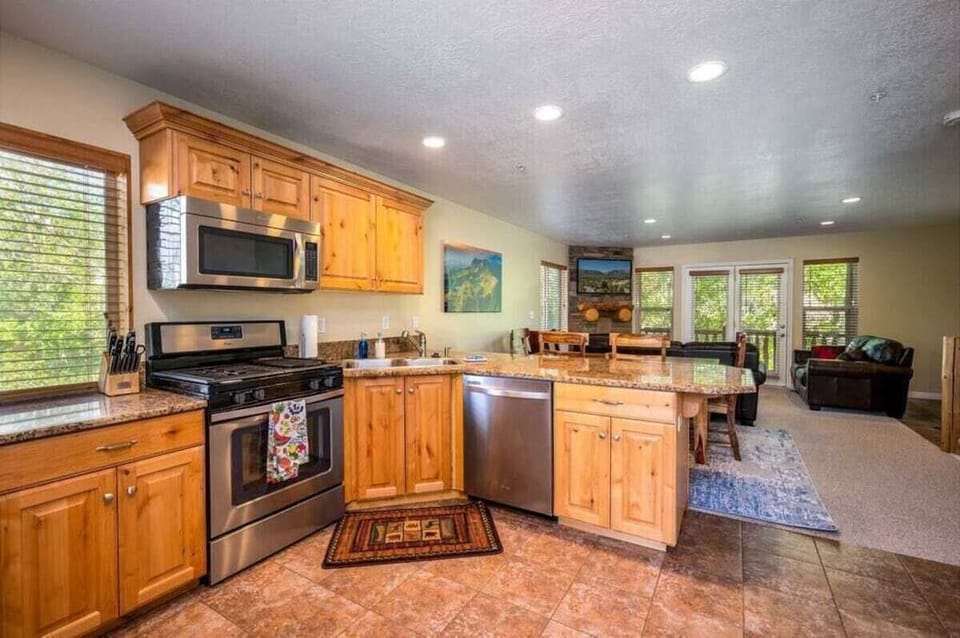 The gourmet kitchen features a breakfast bar with seating and is equipped with stainless steel appliances, including a microwave, gas stove, and spacious refrigerator.