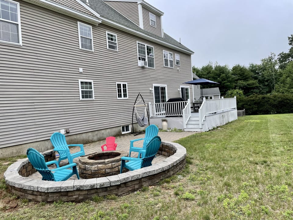 Back patio w/fire pit & Adirondack chairs and swinging hammock chair.