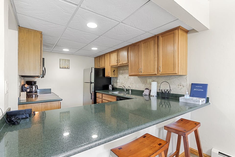 plentiful cabinets and counter space with a breakfast bar and 2 bar stools 