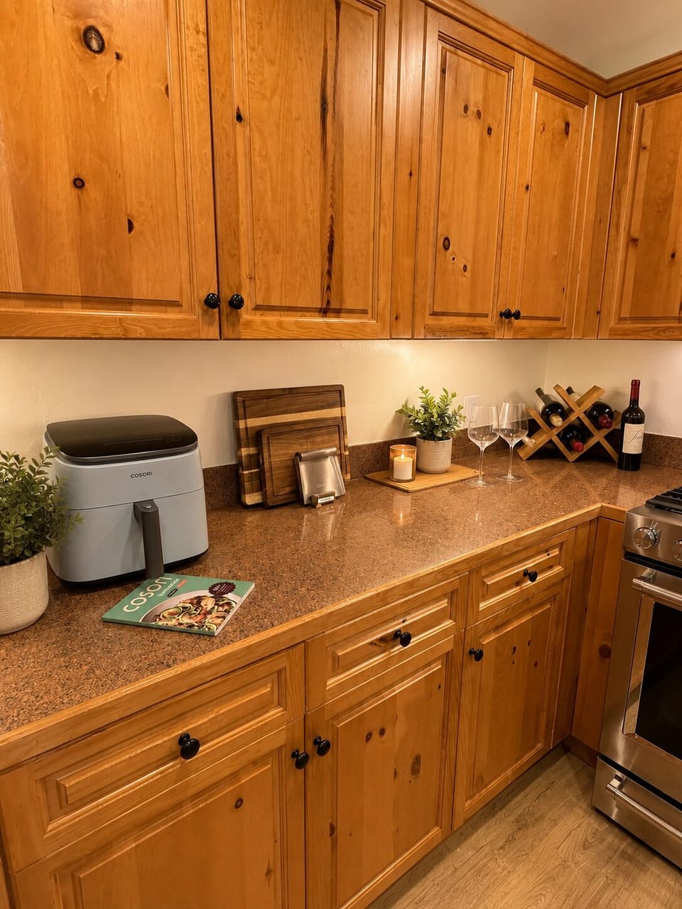 Your fully equipped kitchen invites you to cook at home with warm wood cabinetry, ample counter space, and thoughtful touches like a wine rack and fresh greenery to make every meal feel special.