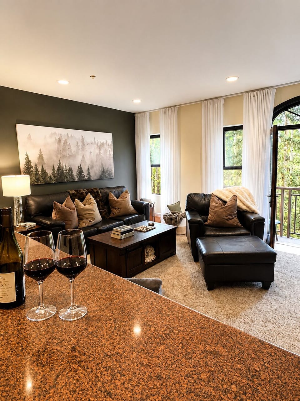 Settle into plush leather seating as natural light filters through your private balcony door, framing forest views. Pour a glass of wine at the gleaming bar and sink into this inviting retreat.