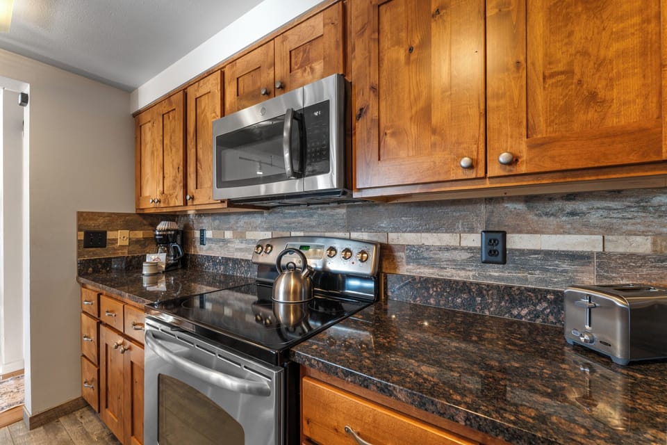 Updated full size kitchen with granite countertops, stainless steel appliances, and breakfast bar for additional seating