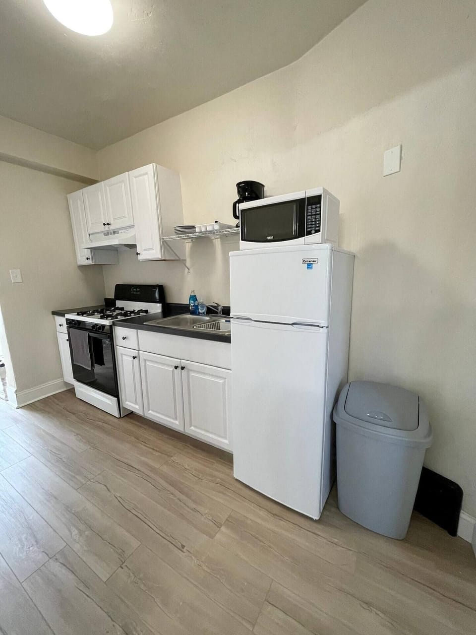 Galley style kitchen furnished with all the necessities to prepare meals like pots/pans, baking dishes, cooking knives, microwave and coffee maker
