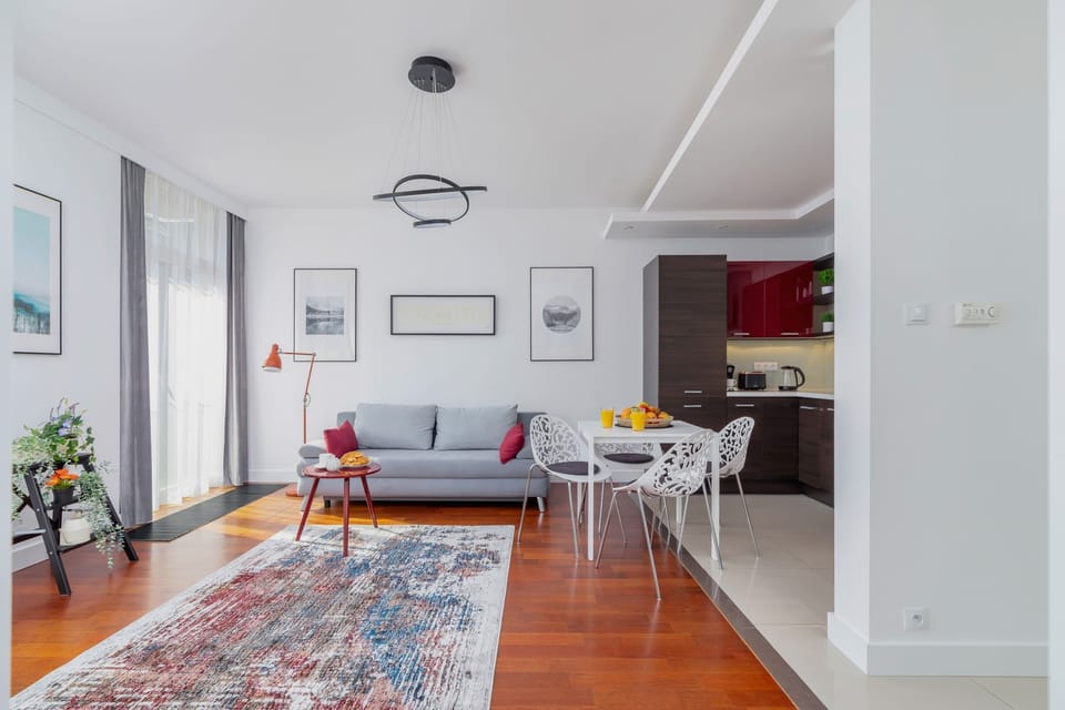 The harmonious combination of living room and kitchenette gives the room functionality. There is a carpet on the floor and long curtains hang in the windows, which add cosiness to the room.