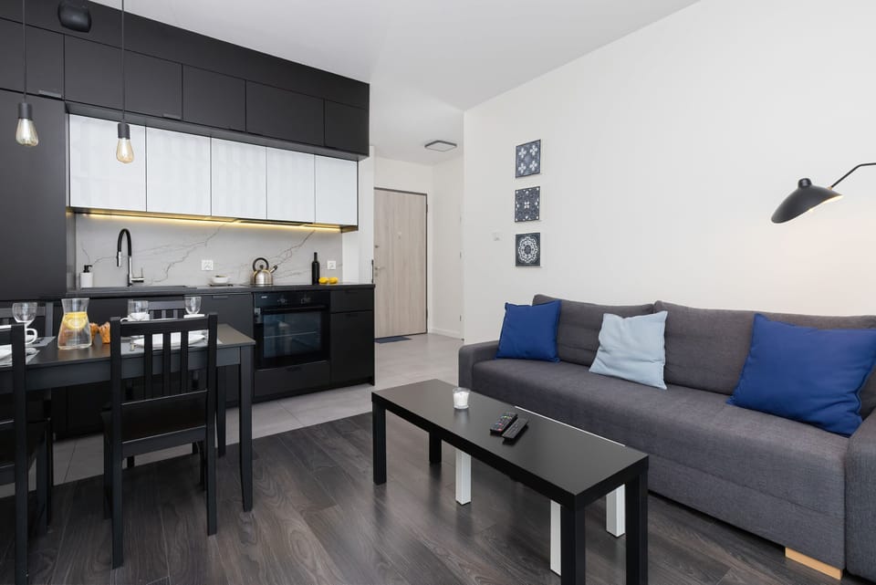 A modern living room featuring a grey sectional sofa with blue cushions, complemented by a coffee table and minimalist decor.