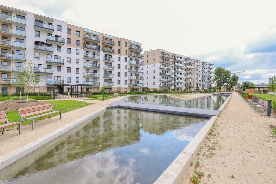 A small outdoor lake surrounded by seating areas, adding recreational value to the residential complex.