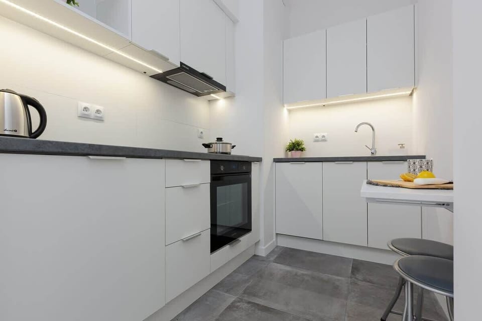 A sleek, modern kitchen with clean, white cabinets, stainless steel appliances, and a stylish minimalist design, creating a bright and efficient cooking space.