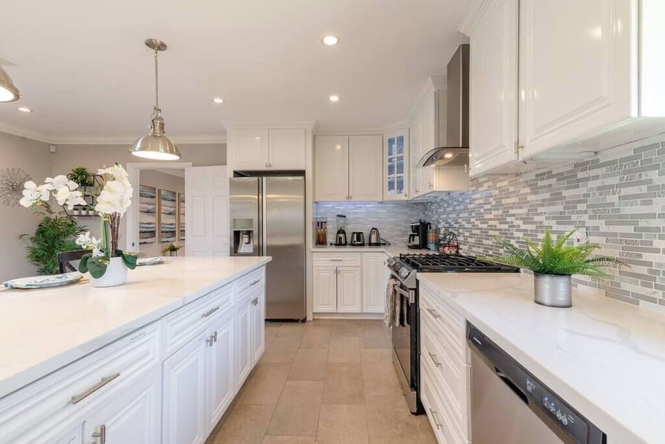 The newly remodeled kitchen with custom quartzite counter top, bar-style island counter, new sliding-in gas cooking range with built in oven, inviting motion-sensitive LED illuminating lighting throughout cabinets.