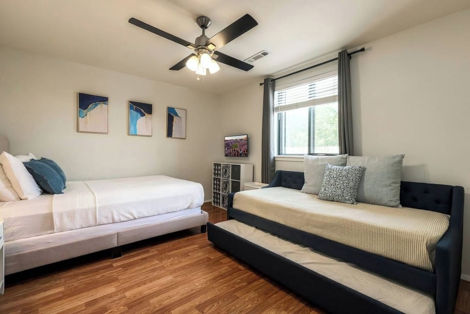Guest bedroom equipped with a queen bed, twin daybed with pull-out trundle, and ceiling fan.