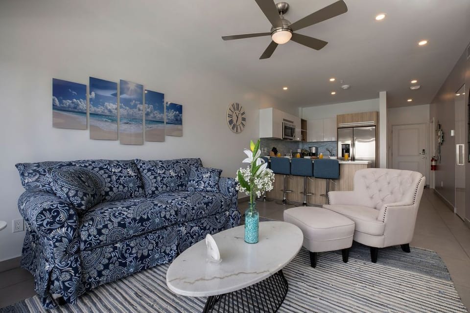 Sink into the plush blue sofa and relax in your bright, airy living space complete with modern kitchen, stylish furnishings, and a ceiling fan to keep you cool.