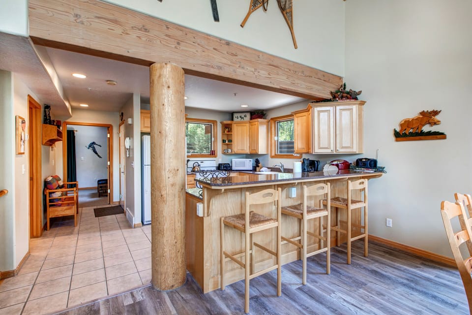 Fully Equipped Kitchen with vast counter-space, stone countertops, Whirlpool appliances, and bar seating for three