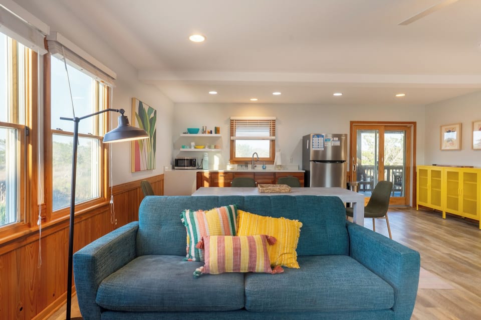 Relax in your bright open-plan living space with modern kitchen and cheerful teal sofa—perfect for unwinding after exploring.