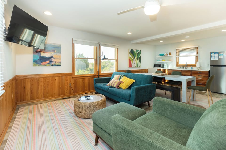 Relax in your stylish living space with colorful seating, warm wood accents, and a fully equipped kitchen perfect for your getaway.