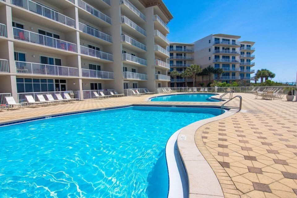 Dive into crystal-clear waters at your resort-style pool, surrounded by spacious lounge chairs and swaying palms under endless blue skies.