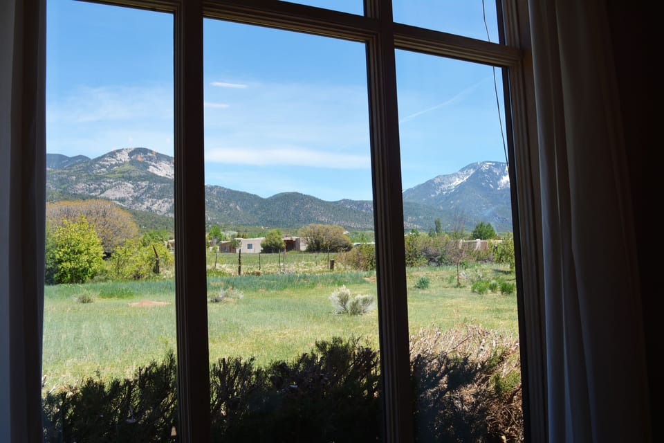 Close up view of Taos Mountain background and horse / cow pasture from living room round table.